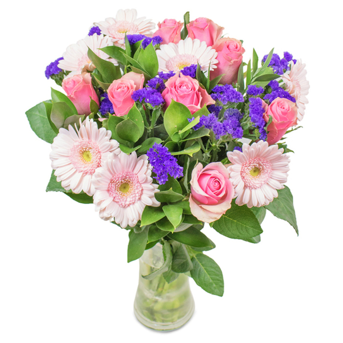 This eye-catching bouquet, crafted in Lee and inspired by the neighbourhood's leafy charm, features an artful arrangement of around 7-9 pink roses-most just beginning to open, showing off their classic spiral shapes and soft, full petals. These are paired beautifully with approximately 5-7 pale pink gerbera daisies, their large round faces and delicate lighter centers a gentle, uplifting presence. Scattered amongst the blooms are pockets of vivid purple statice, each small cluster offering a striking pop of colour and a tactile contrast against the blush tones. Lush, deep green foliage, abundant at the base, fills the bouquet with a vibrant sense of freshness-like the greenery found after light rain in local parks. Presented in a transparent vase whose waterline and neat stems are clearly visible, the arrangement suggests a hand-delivered gift, perhaps for a Lee birthday, Mother's Day, or anniversary. The soft interplay of colour and texture conveys joy, celebration, and a modern sense of affection, all shaped by the expert touch of Flowers Lee. It's a bouquet perfectly at home on a Lee kitchen table or greeting guests by the front door, radiating both cheer and gentle sophistication.